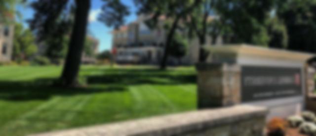 a blurred photo of the Carroll University sign and Main Lawn.